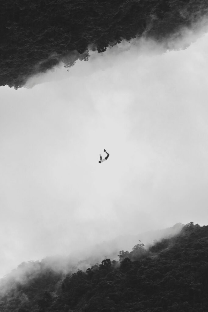 Silhouetted person mid-air against a fog and forest backdrop in Shiding District, Taiwan.