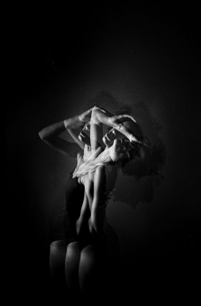 A black and white double exposure photograph of a woman striking graceful poses against a dark background.